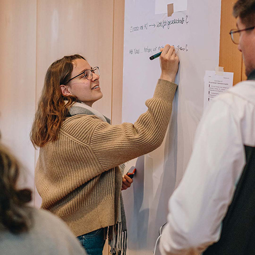 Eine junge Studentin schreibt mit einem schwarzen Edding auf ein Flipchart.