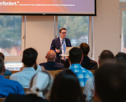 Prof. Dr. Eduard Ferderer hält seine Antrittsvorlesung in Bad Liebenzell. Im Vordergrund sind unscharf die Hinterköpfe der Zuschauerinnen und Zuschauer zu sehen.