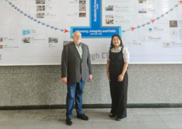 Dr. Friedemann Burkhardt steht gemeinsam mit einer Frau vor einer Wandgrafik an der Handong Global University in Südkorea. Auf der Grafik sind die Worte ‚Honesty, Integrity and Faith‘ zu lesen