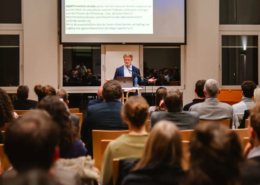 Thomas Kleber hält seine Antrittsvorlesung im Atrium des Missions- und Schulungszentrums in Bad Liebenzell. im Vordergrund ist eine große Menschenmengen, die fokussiert seinem Vortrag zuhört.