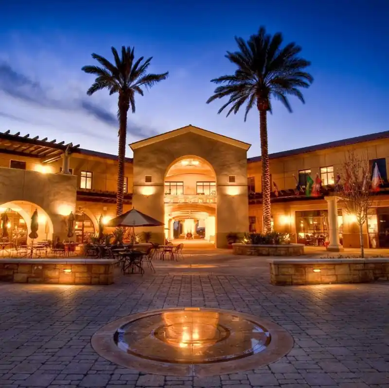 Stimmungsvolle Abendaufnahme des Yeager Centers auf dem Hauptcampus der California Baptist University (CBU), einer Partnerhochschule der Internationalen Hochschule Liebenzell. Zu sehen ist der beleuchtete Innenhof mit mediterraner Architektur, Palmen und einem blauen Abendhimmel.